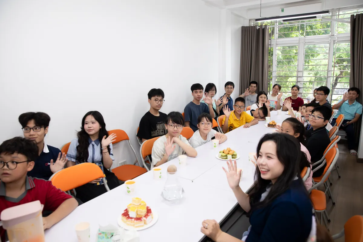 Giáo viên, học sinh và gia đình ngồi quanh bàn trong buổi vinh danh