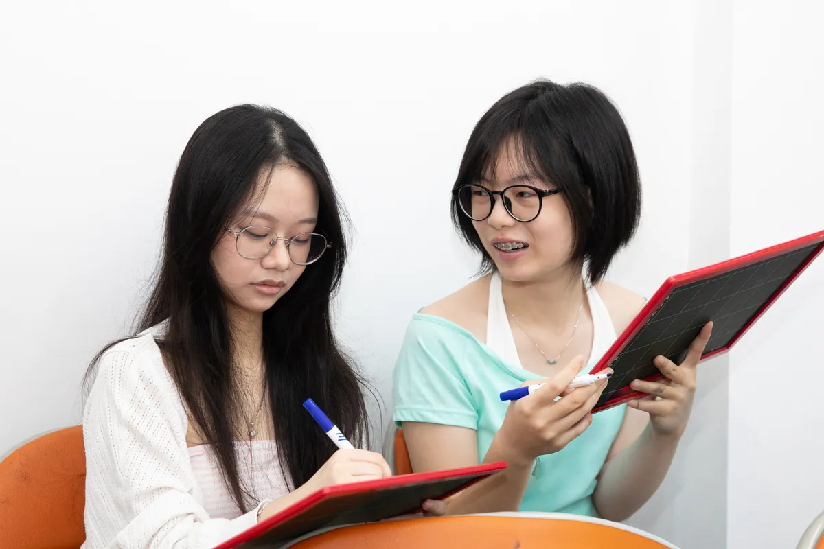 Hai học sinh trao đổi khi viết trên bảng nhỏ
