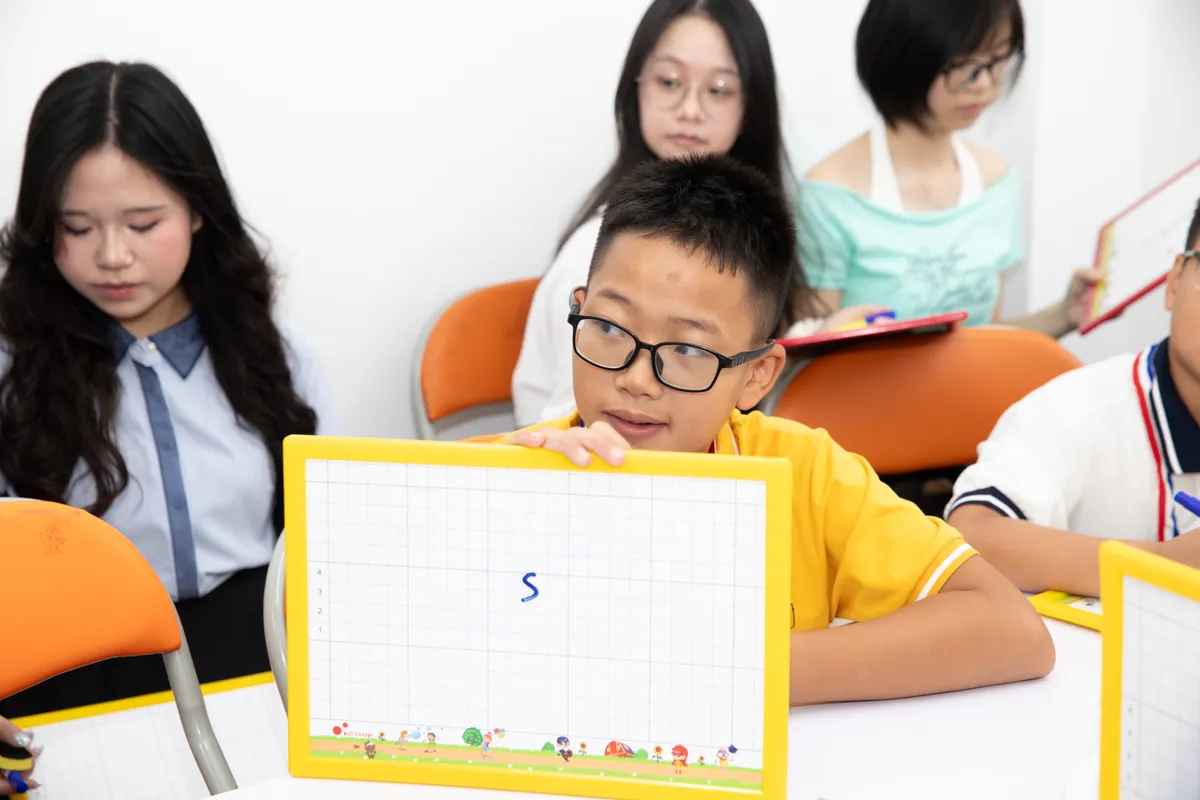 Một học sinh giơ bảng trong khi các bạn tiếp tục hoàn thành câu trả lời