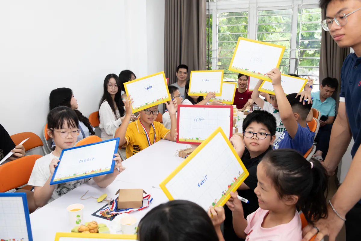 Học sinh quanh bàn giơ bảng trong một hoạt động tại lễ vinh danh của GIANGTES